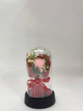 Bouquet of flowers in a glass dome with a red ribbon on a white background