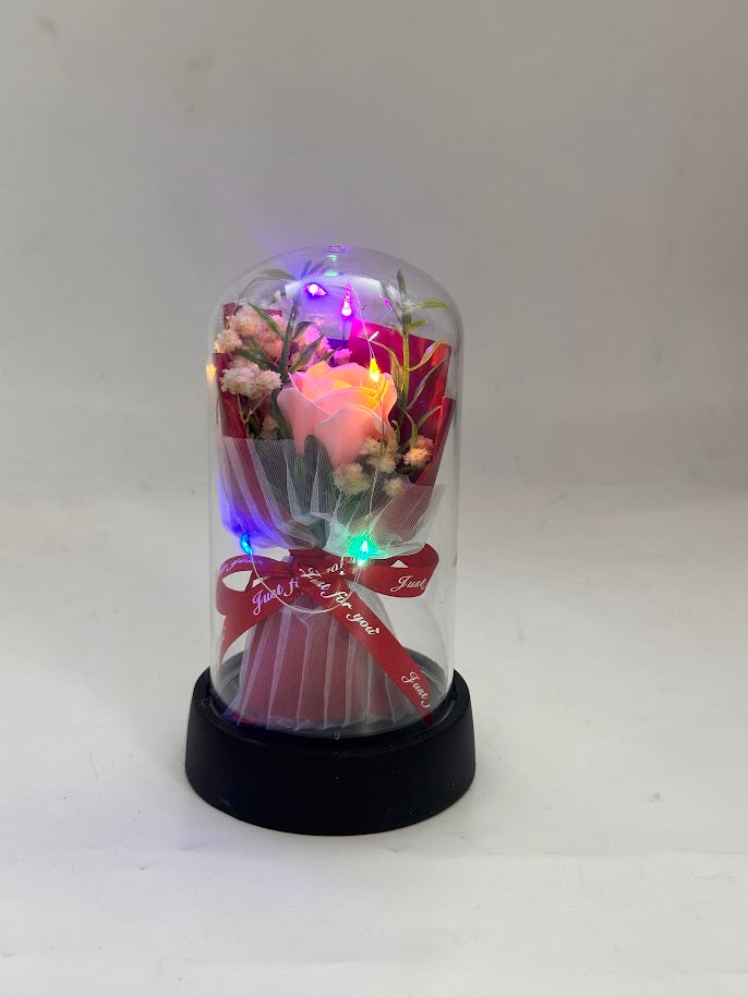 Decorative glass dome with LED lights and a bouquet of flowers on a white background