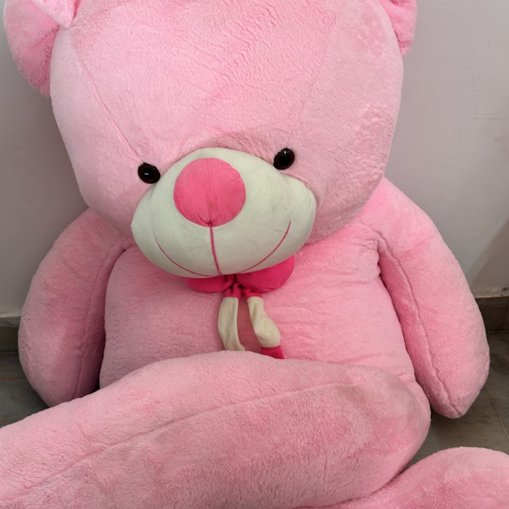 Large pink teddy bear with a red nose on a neutral background
