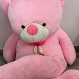 Large pink teddy bear with a red nose on a neutral background