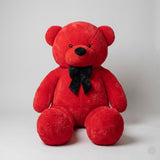 Red teddy bear with a black bow tie on a light gray background