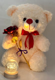 White teddy bear with a red bow holding a gold flower, next to a small glowing orb on a light gray background.