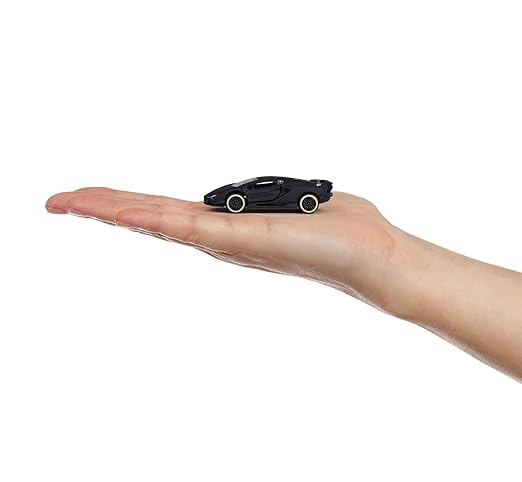 Small black toy car on a person's palm against a white background