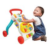 A baby playing with a colorful musical walker with multiple interactive buttons and wheels.