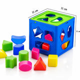 A children's shape-sorting cube toy in bright blue and green, shown with colorful geometric blocks on a white background. Black dimension lines and text indicate 11 cm measurements on the cube sides.