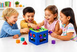 Four young children smiling and playing with a colorful shape-sorting toy cube on a white table in a bright indoor room.