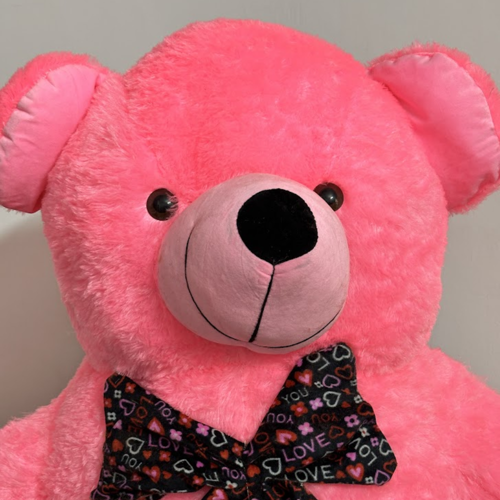 Pink teddy bear with a colorful bow tie on a neutral background